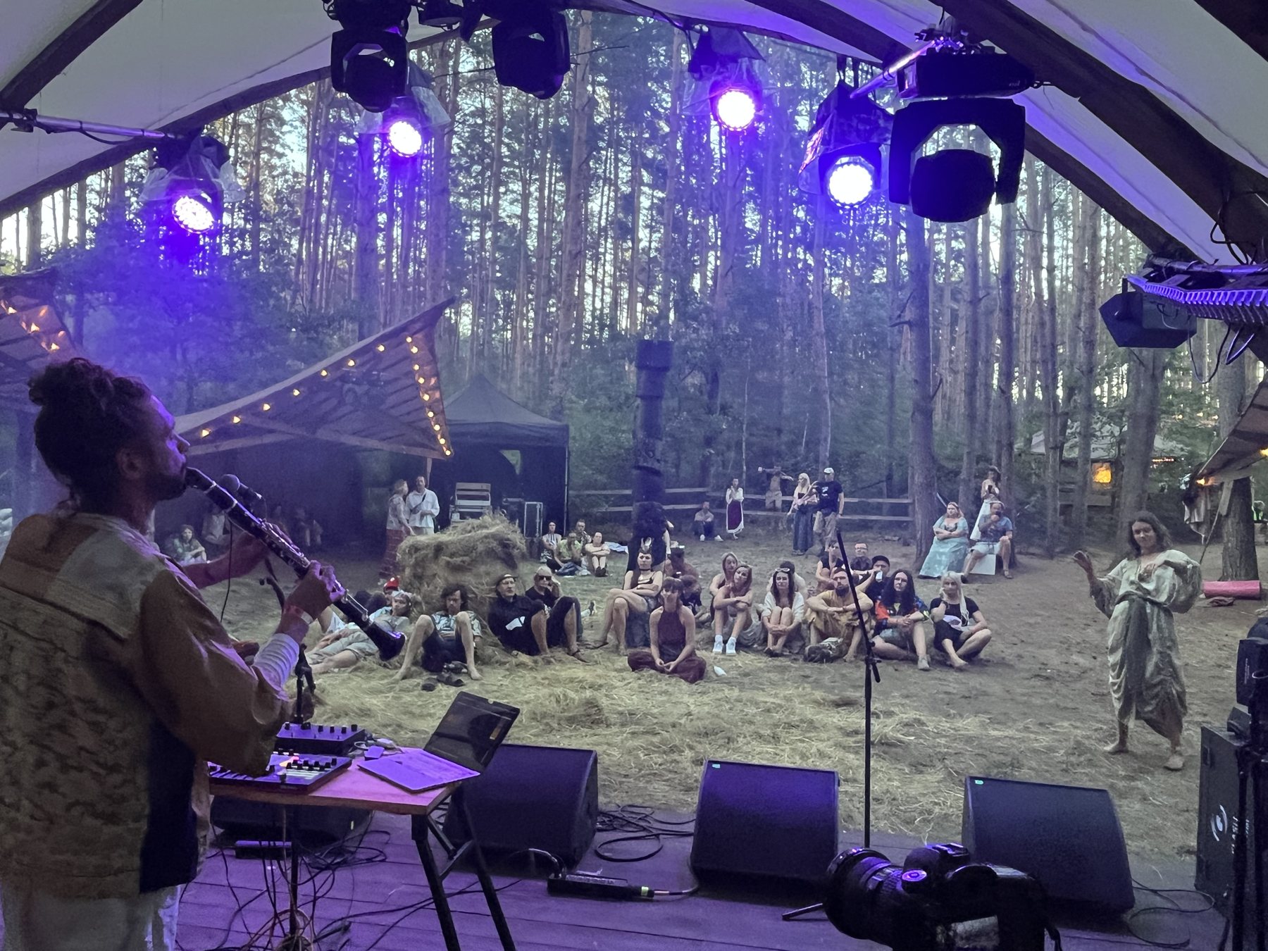 Playing clarinet on the forest stage at Tribalanga, the audience sitting on hay